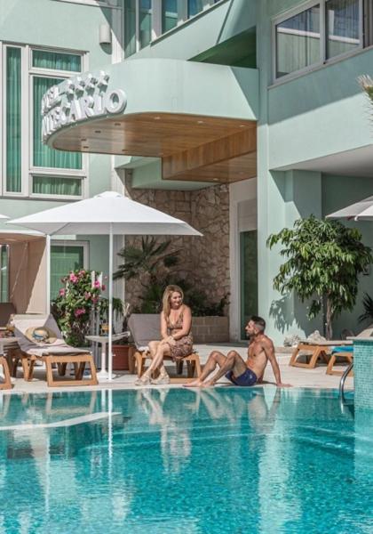 Piscina di un hotel con persone che si rilassano sotto gli ombrelloni.