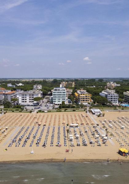 Spiaggia con ombrelloni e edifici sullo sfondo, giornata soleggiata.