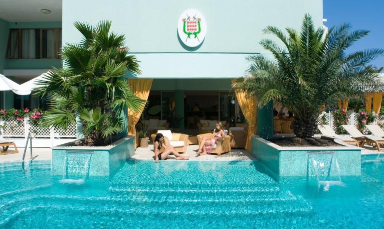 Piscina con palme, cascata e persone che si rilassano.
