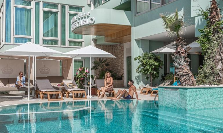 Piscina di un hotel con persone che si rilassano sotto gli ombrelloni.