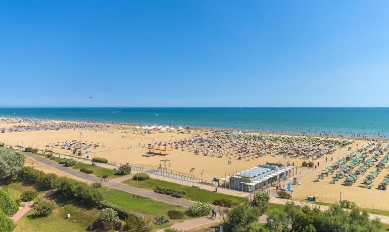 Spiaggia soleggiata con ombrelloni e mare blu, ideale per relax estivo.