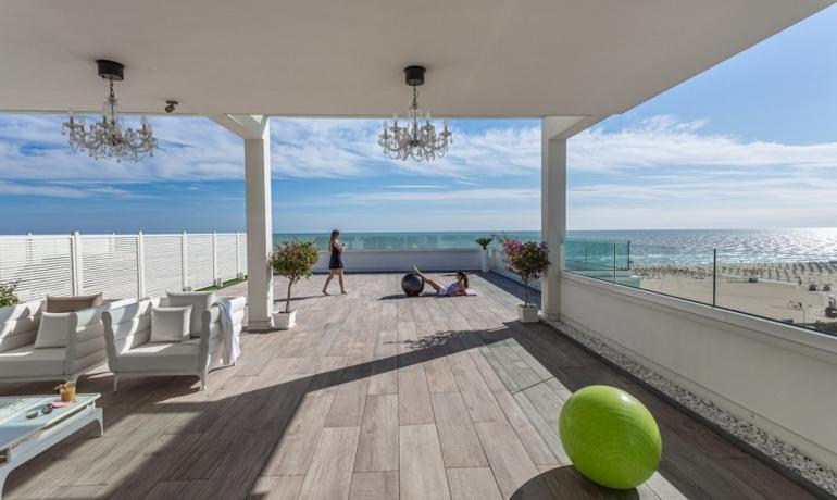 Moderne Terrasse mit Meerblick, weißen Möbeln und Gymnastikbällen.