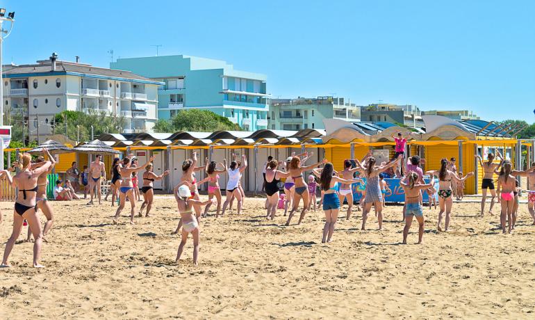 Persone che fanno esercizi aerobici sulla spiaggia in una giornata soleggiata.