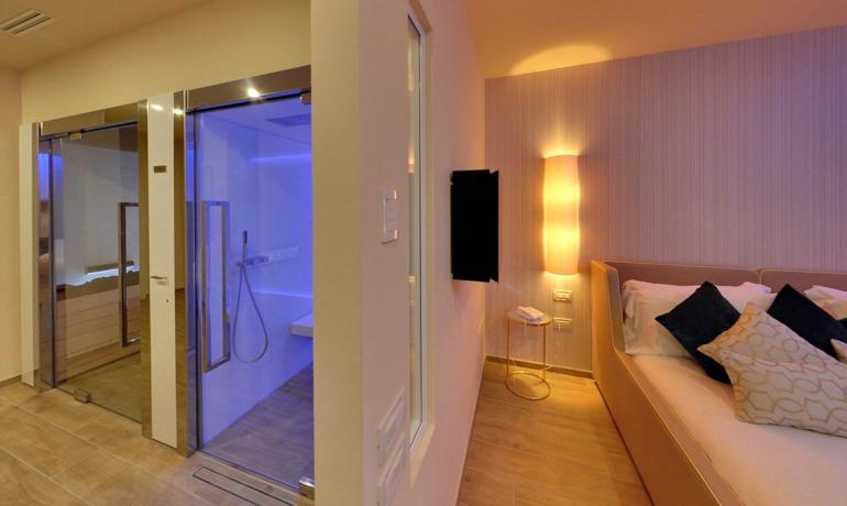 Camera moderna con doccia illuminata e letto accogliente.
