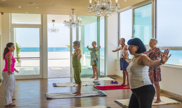 Lezione di yoga in una sala con vista mare.