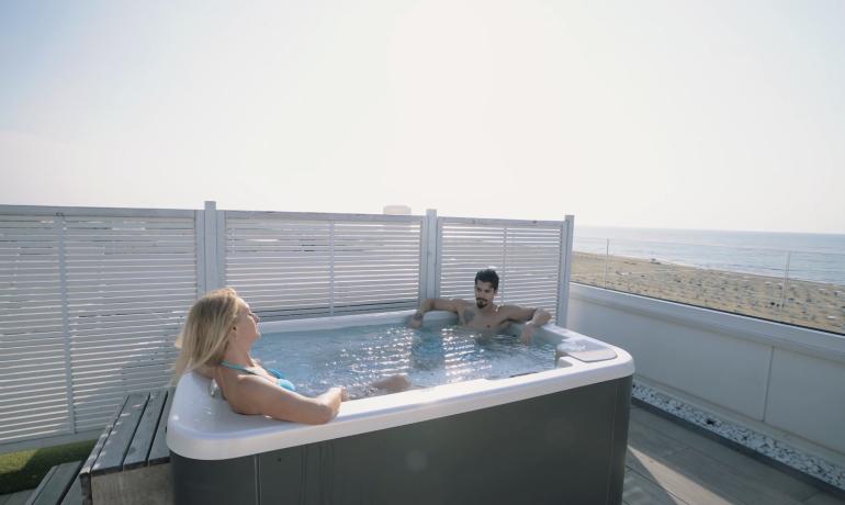 Due persone rilassano in una vasca idromassaggio con vista sul mare.