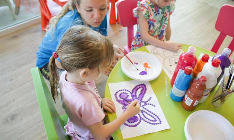 Children painting with bright colors at a table.