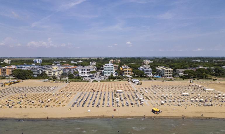 Spiaggia con ombrelloni e edifici sullo sfondo, giornata soleggiata.