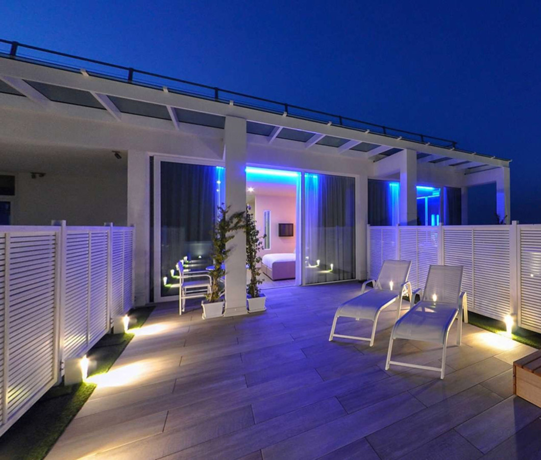 Terrazza moderna con lettini e vasca idromassaggio illuminata di notte.