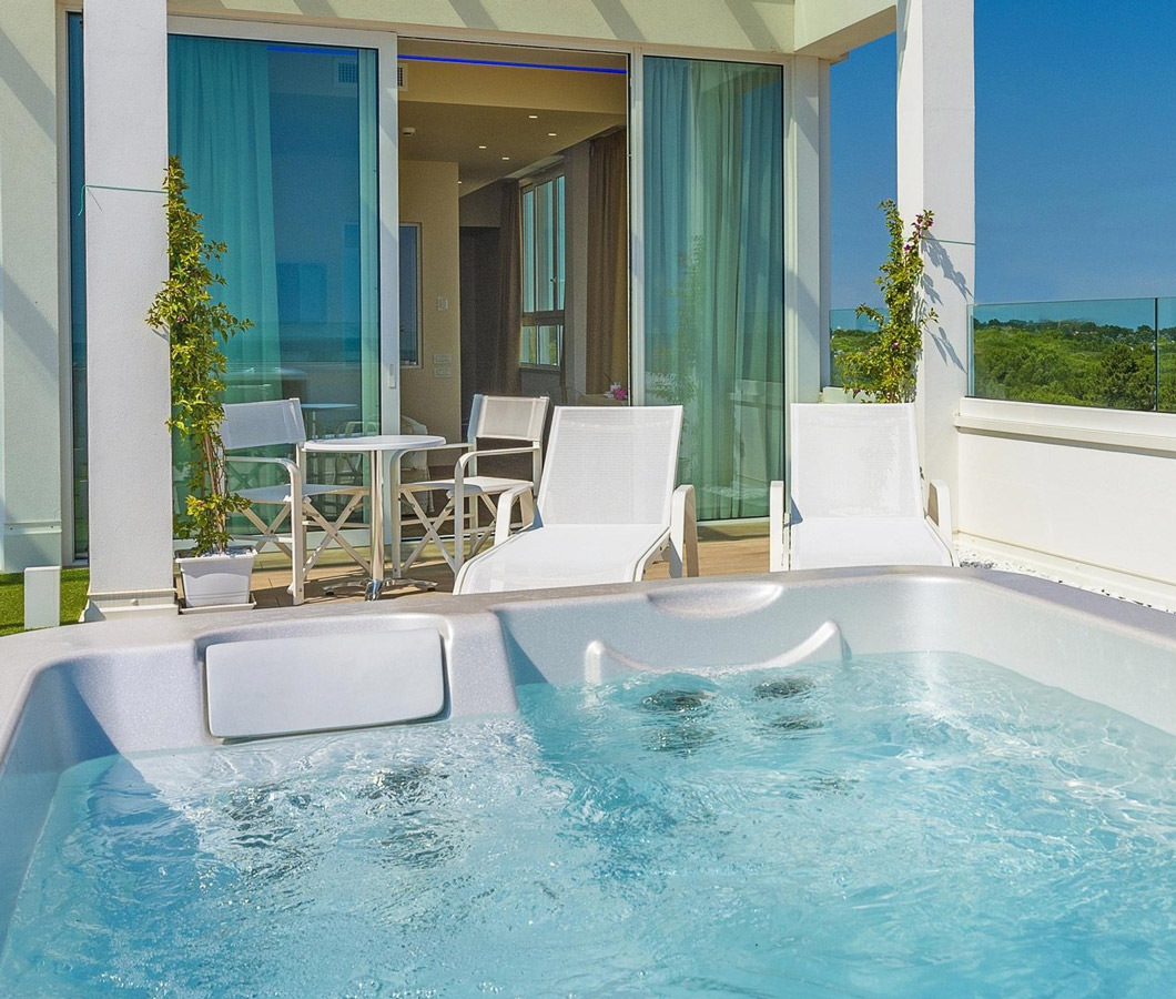 Terrazza con jacuzzi, sedie a sdraio e vista panoramica sul verde.