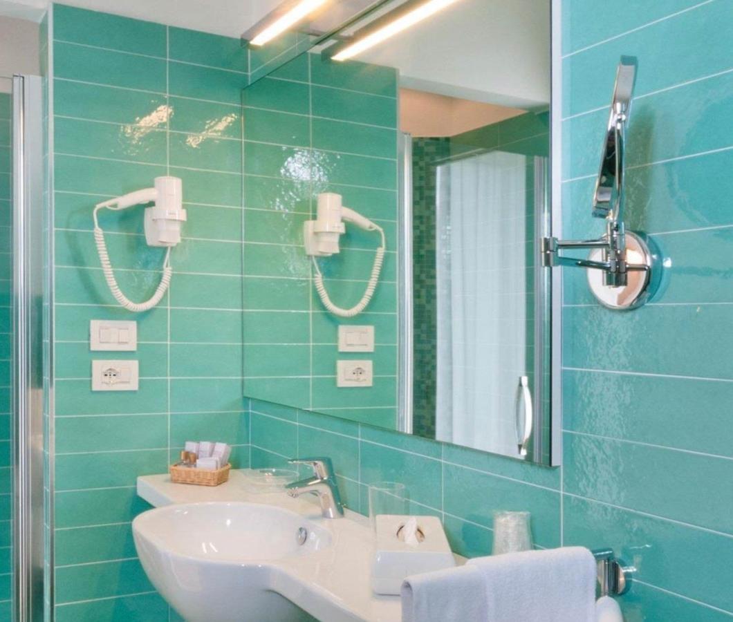 Bagno moderno con piastrelle verdi e accessori eleganti.