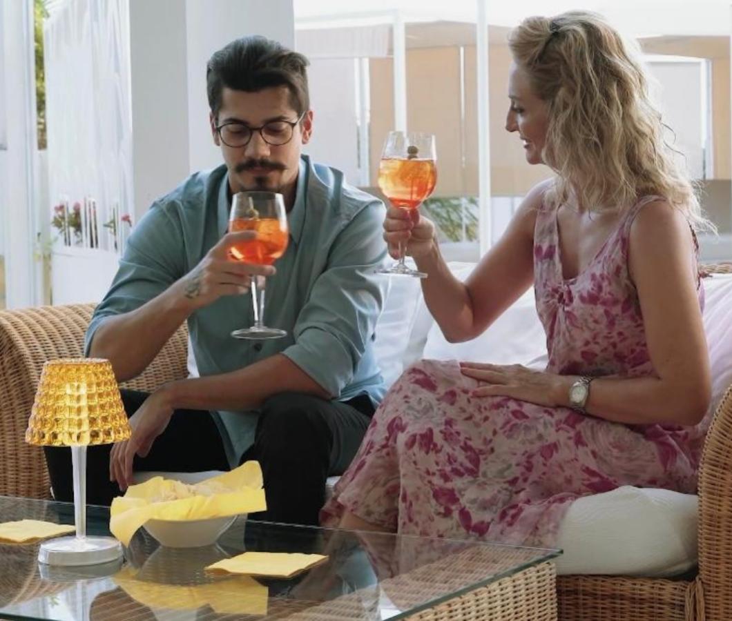 Coppia brinda con cocktail in un ambiente rilassato.