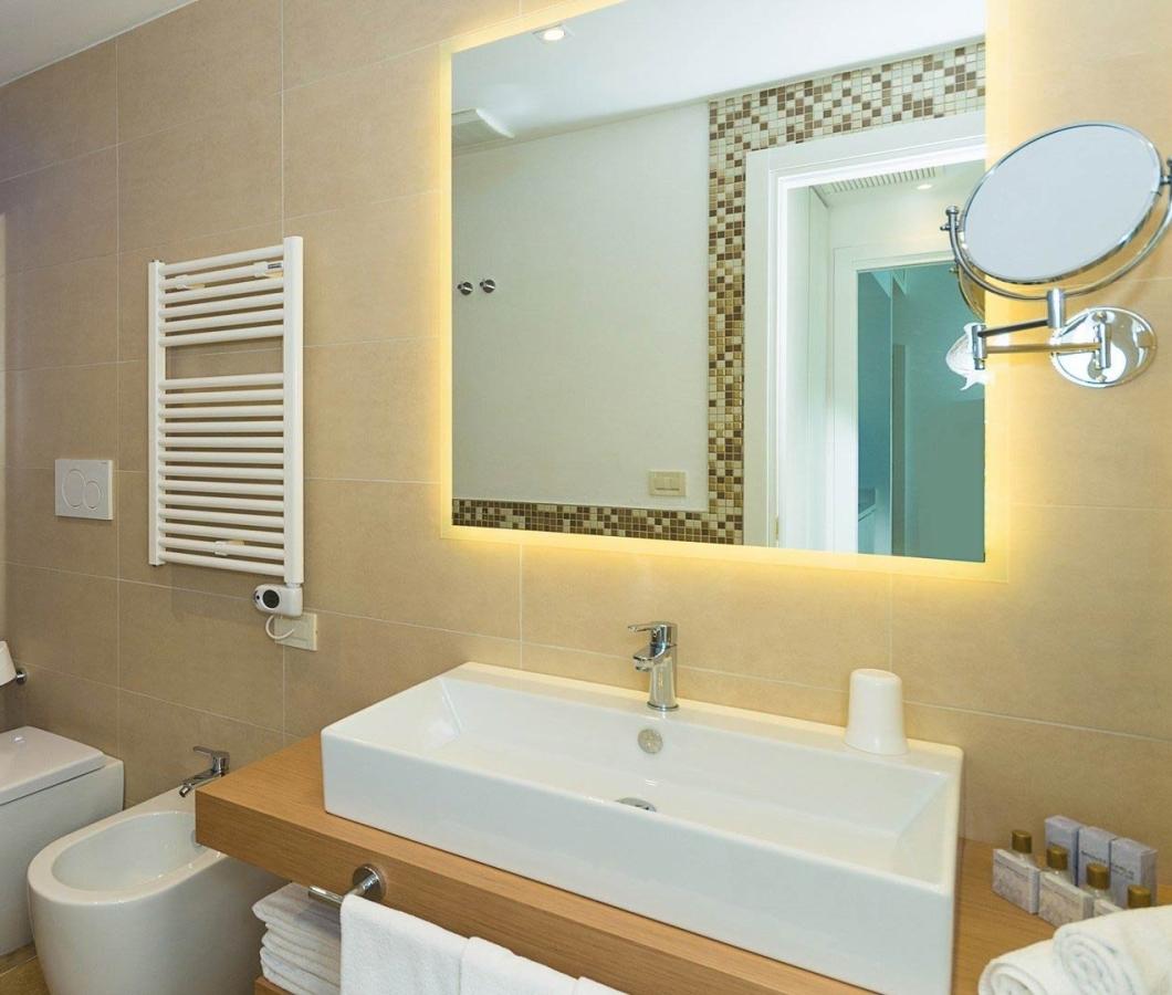 Modernes Badezimmer mit Mosaikdusche und beleuchtetem Spiegel.