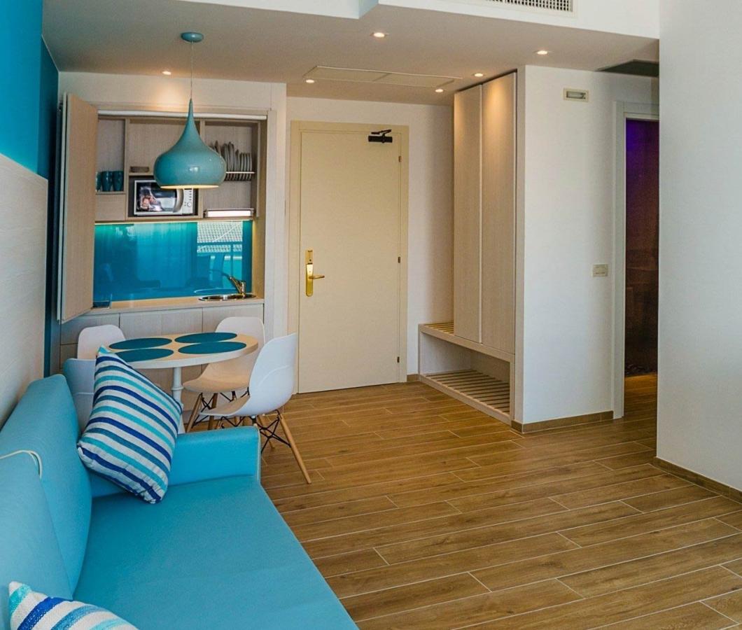 Modernes Wohnzimmer mit blauem Sofa, TV und Küchenzeile.
