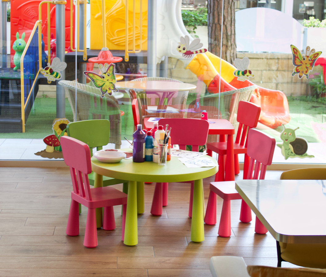 Area giochi colorata con tavoli e sedie per bambini.