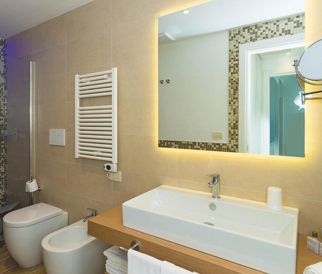 Bagno moderno con doccia a mosaico e specchio retroilluminato.