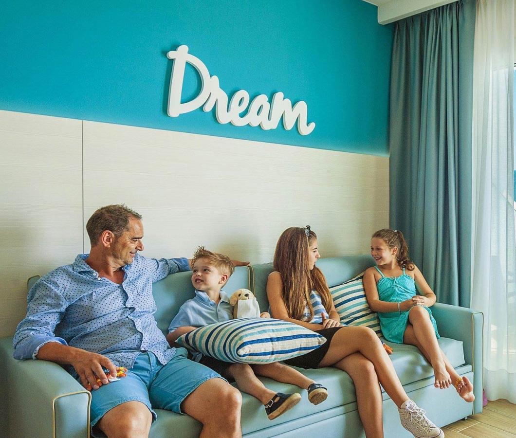 Famiglia rilassata in soggiorno vista mare, atmosfera serena e luminosa.