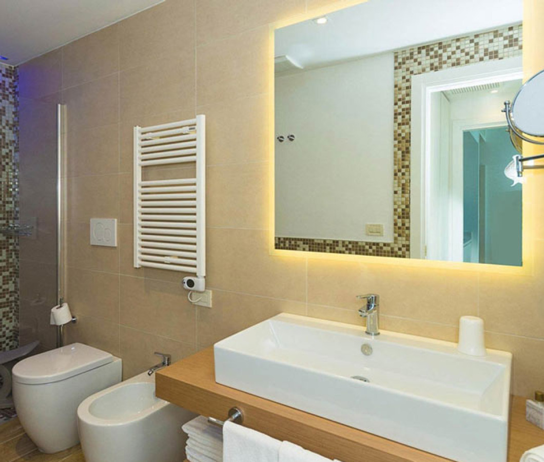 Bagno moderno con doccia a mosaico e specchio retroilluminato.