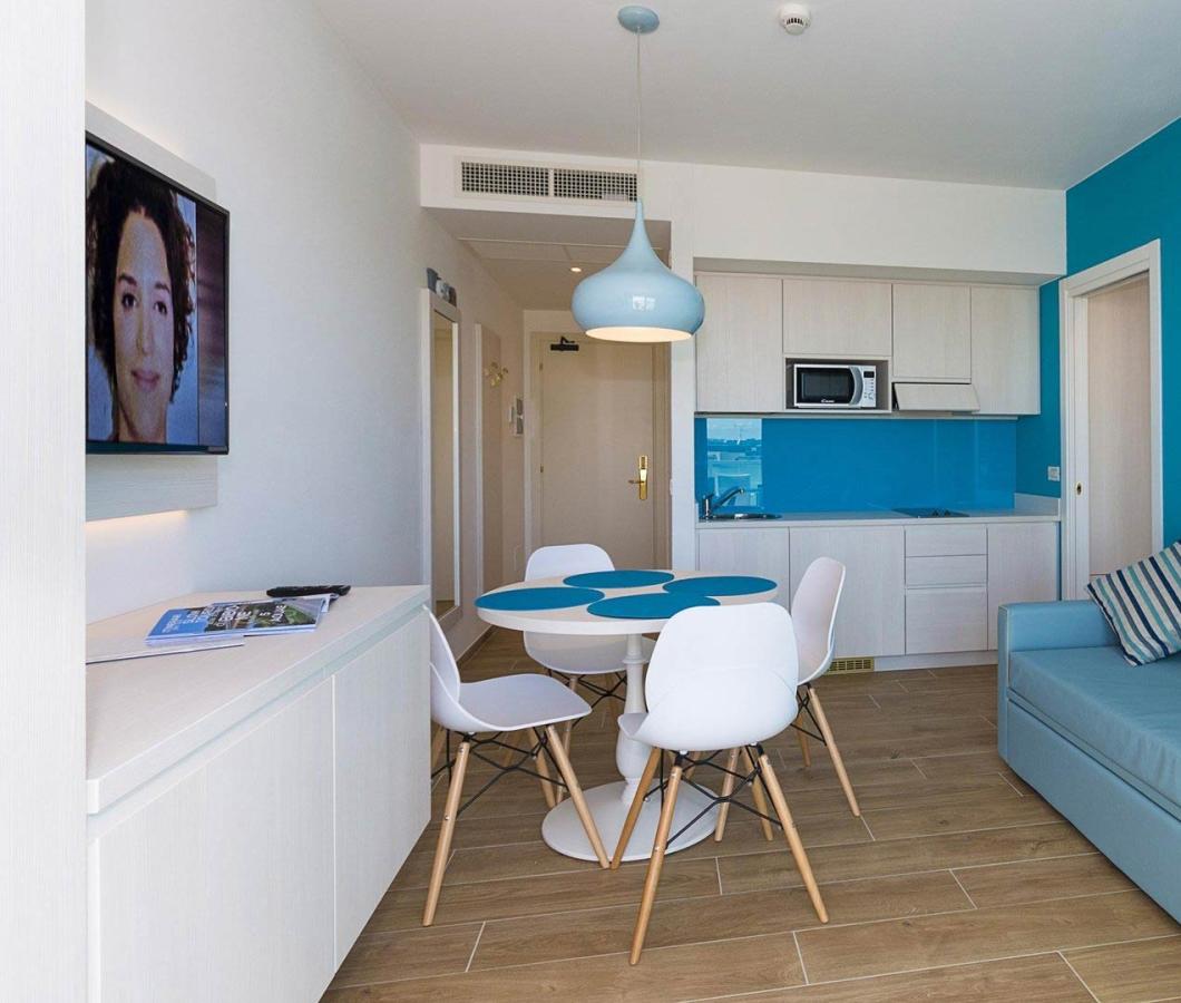 Soggiorno moderno con cucina, divano blu e TV.