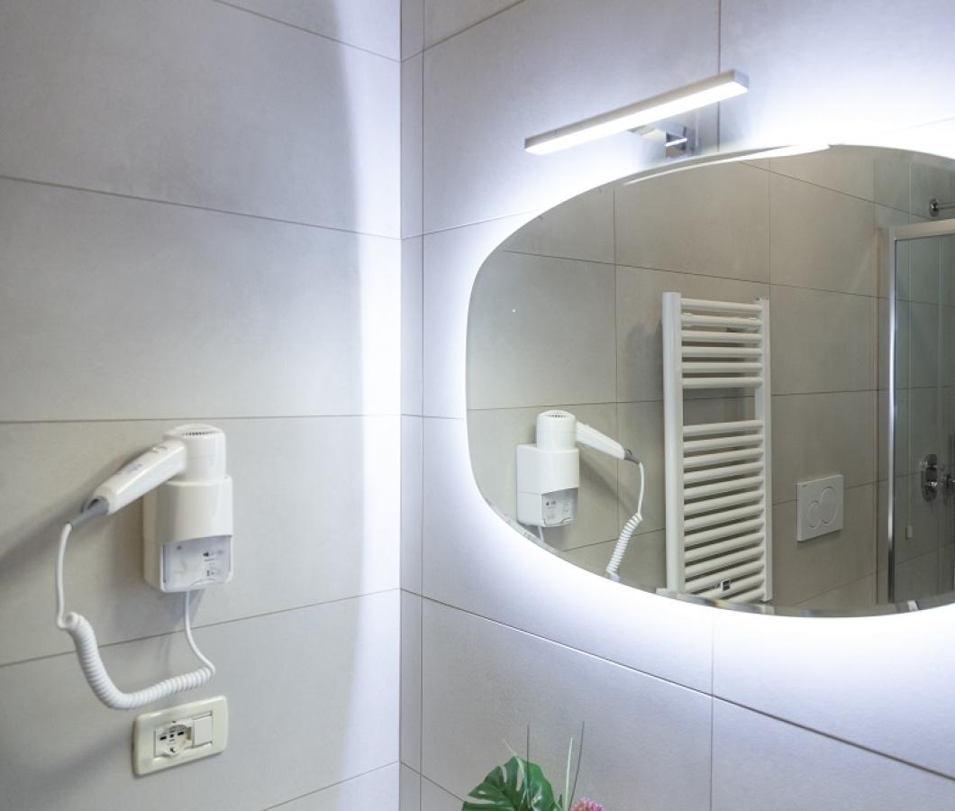 Bagno moderno con specchio illuminato e asciugacapelli.