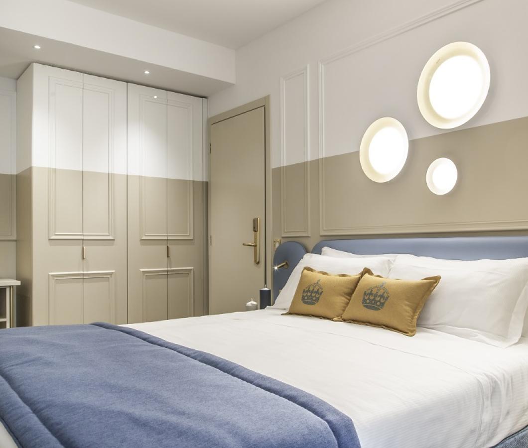 Camera moderna con letto matrimoniale e illuminazione circolare a parete.