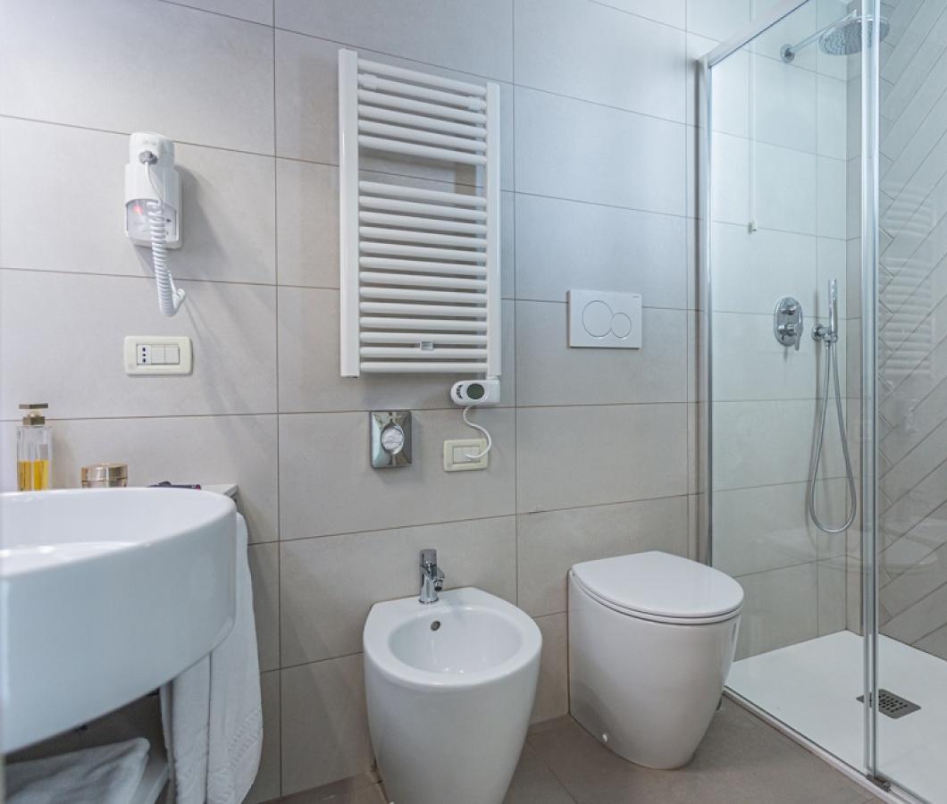 Bagno moderno con doccia, bidet e asciugacapelli.