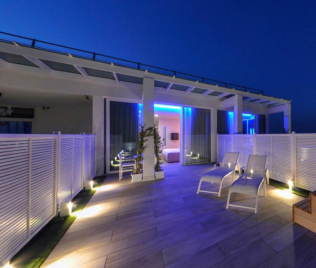 Terrazza moderna con lettini e vasca idromassaggio, illuminazione blu.