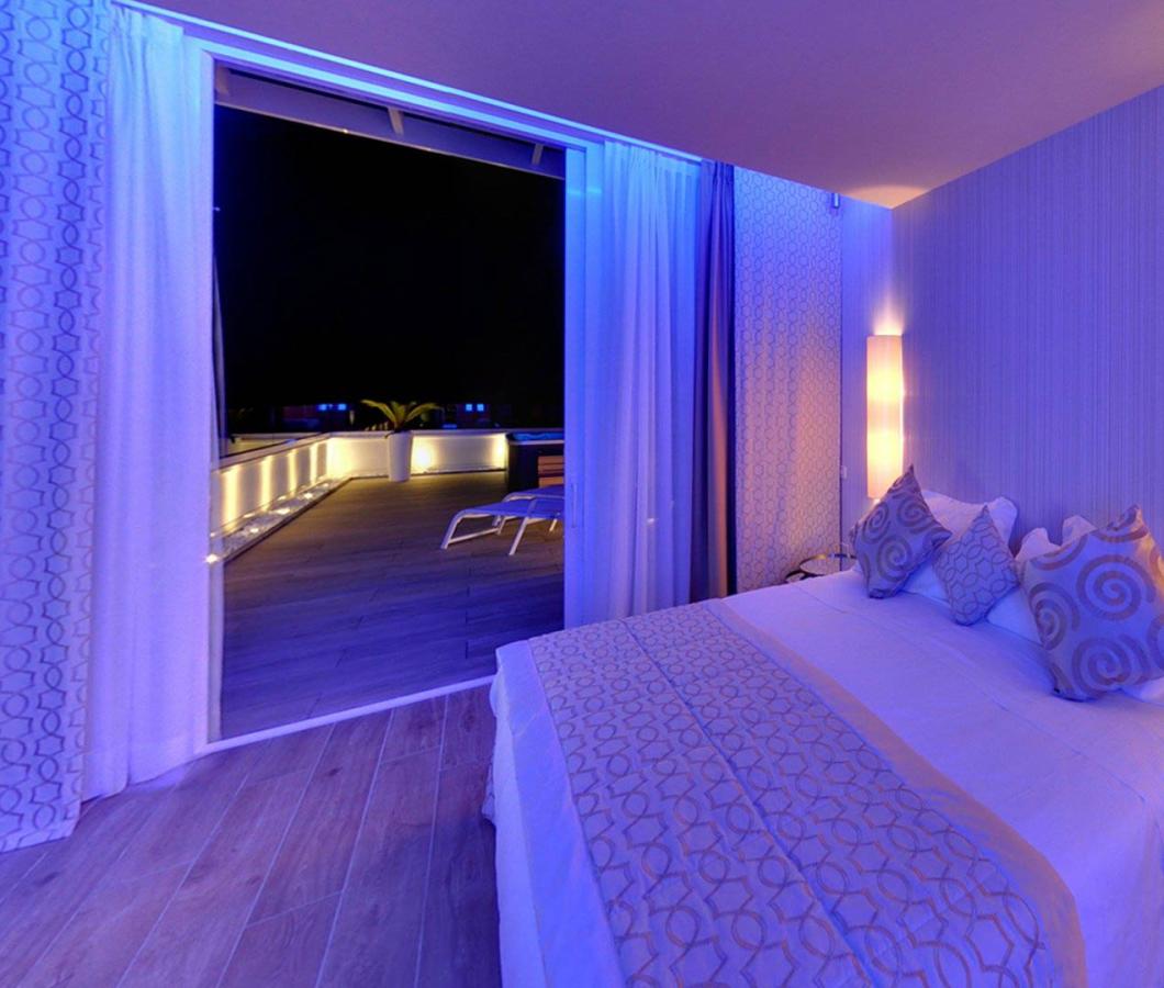 Camera moderna con letto e terrazza illuminata di notte.