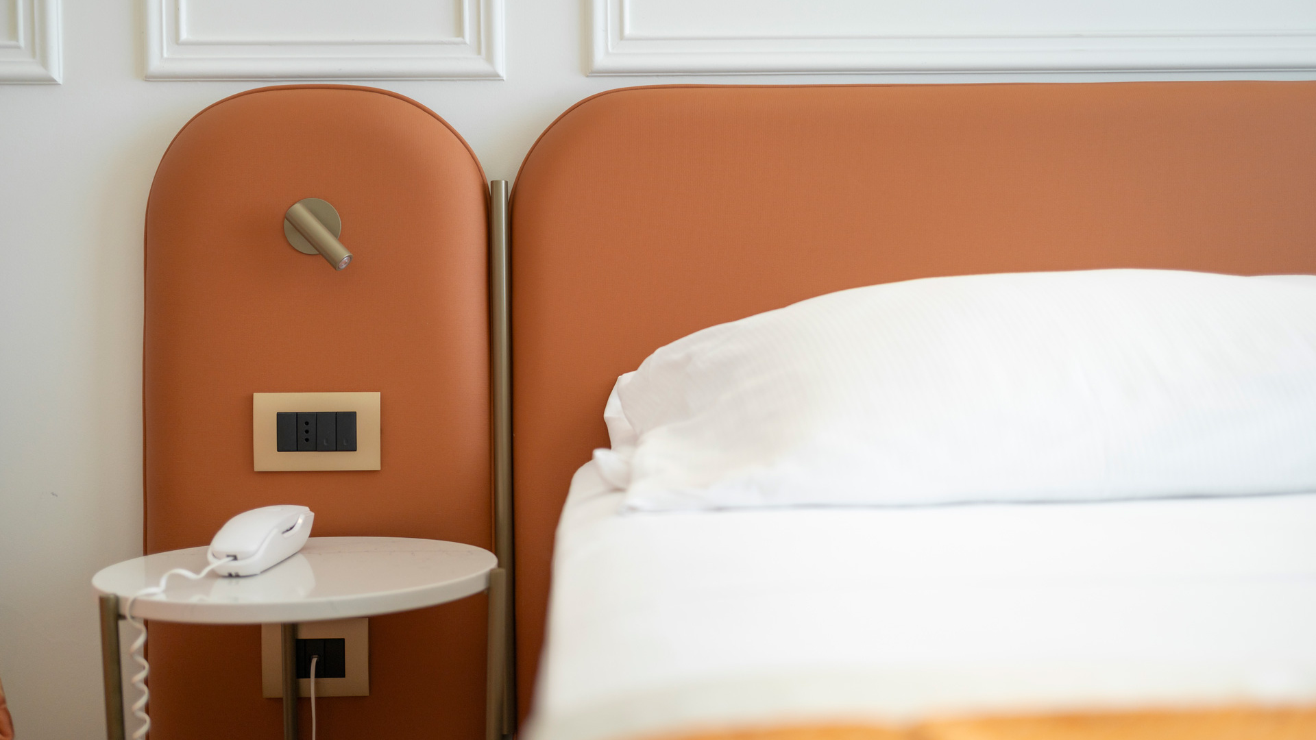 Hotelzimmer mit Bett, Nachttisch und Telefon.