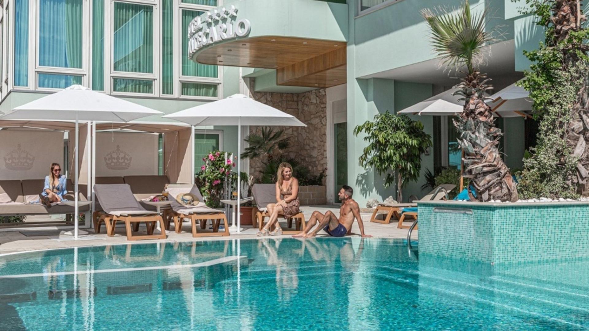 Piscina all'aperto con lettini e ombrelloni in un hotel moderno.