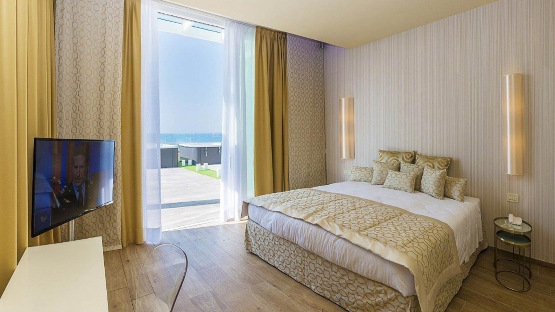 Camera moderna con vista mare, TV e decorazioni dorate.