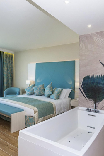 Camera moderna con vasca, letto e decorazioni blu.