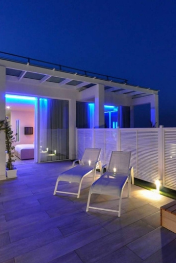 Terrazza moderna con luci blu e sedie a sdraio di notte.
