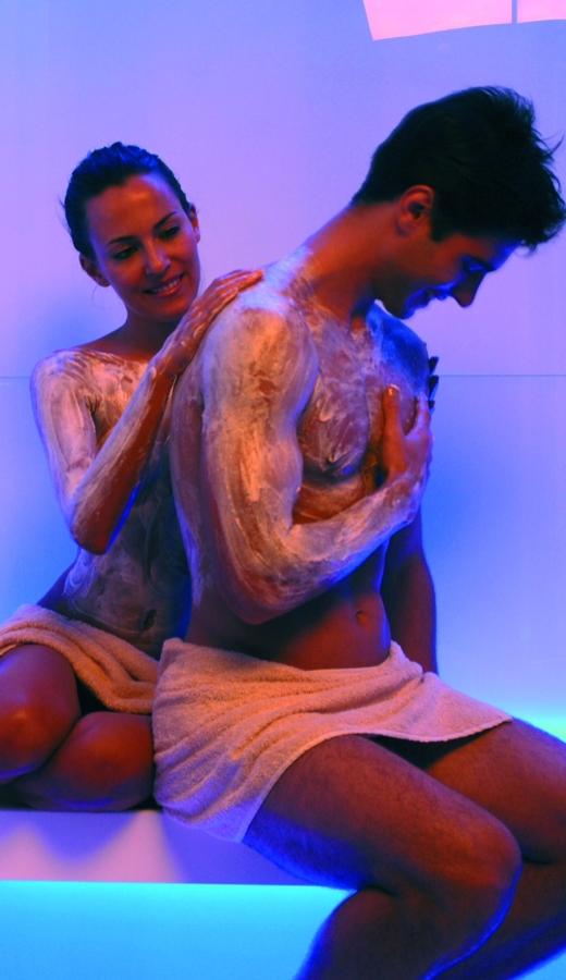 Coppia rilassata in spa con trattamento corpo e asciugamani.
