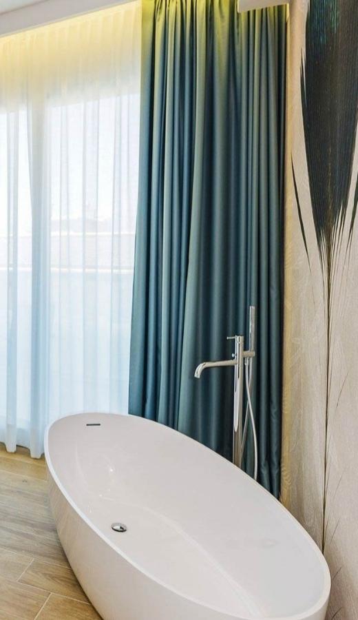 Moderne Badewanne mit eleganten Vorhängen und Holzboden.