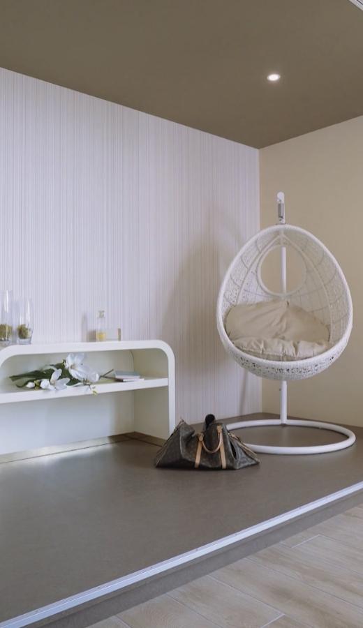 Interno moderno con sedia sospesa e mensola minimalista.