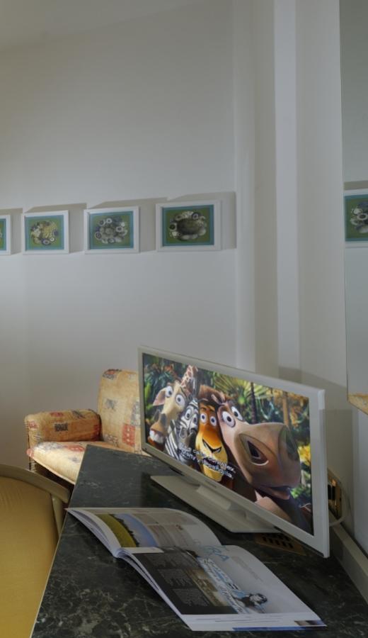 Fernseher mit Cartoon an, offenes Magazin auf Marmortisch.