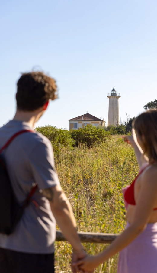 Coppia osserva un faro in lontananza, mano nella mano.