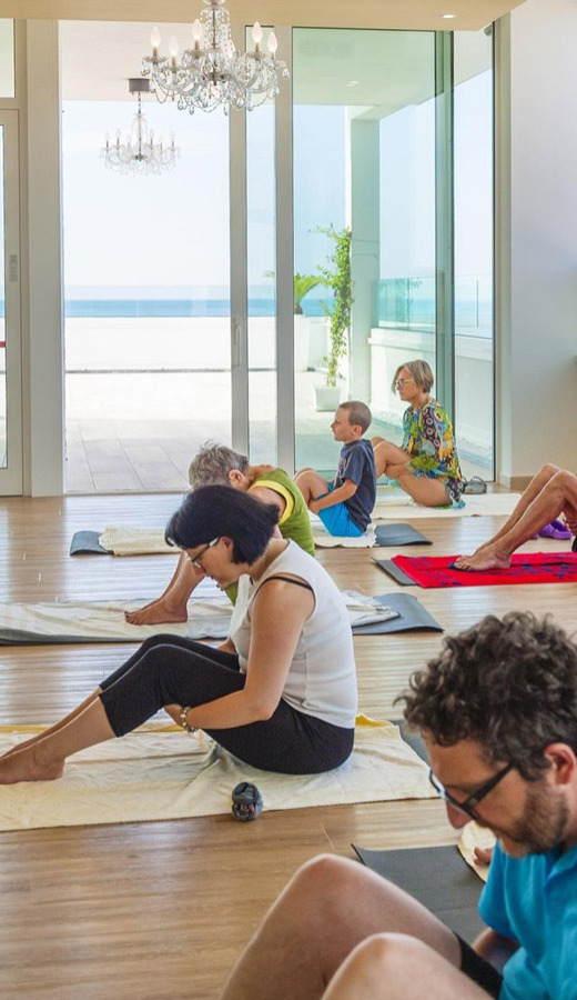 Menschen praktizieren Yoga in einem Raum mit Meerblick.