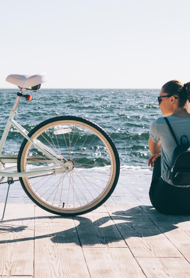 Persona seduta vicino al mare con bicicletta.