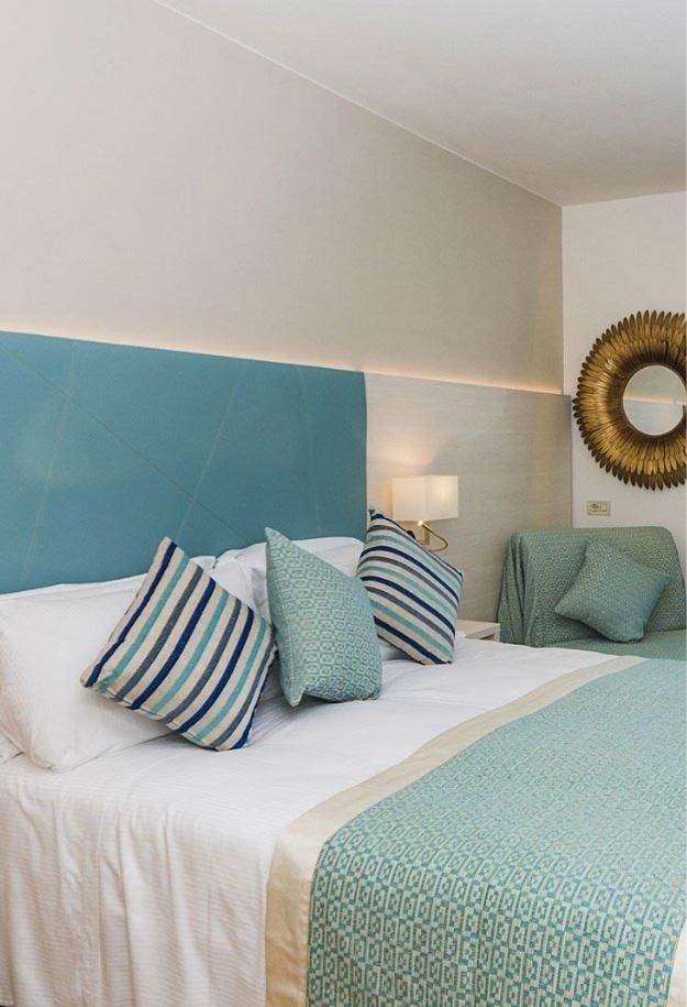 Camera da letto elegante con cuscini blu e specchio decorativo.