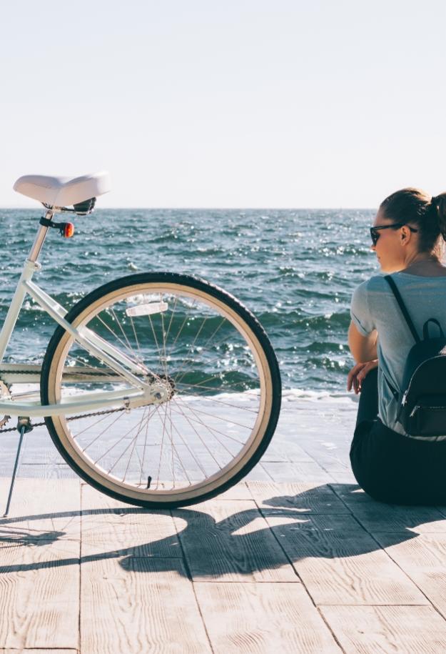 Persona seduta vicino al mare con una bicicletta.