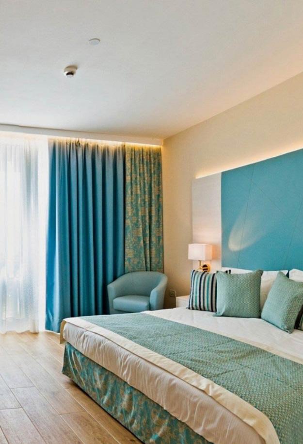 Camera da letto moderna con tende blu e letto matrimoniale.