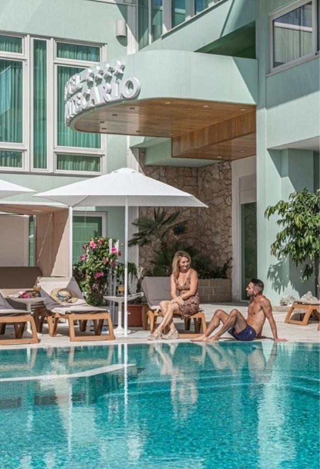 Due persone rilassate a bordo piscina di un hotel moderno.