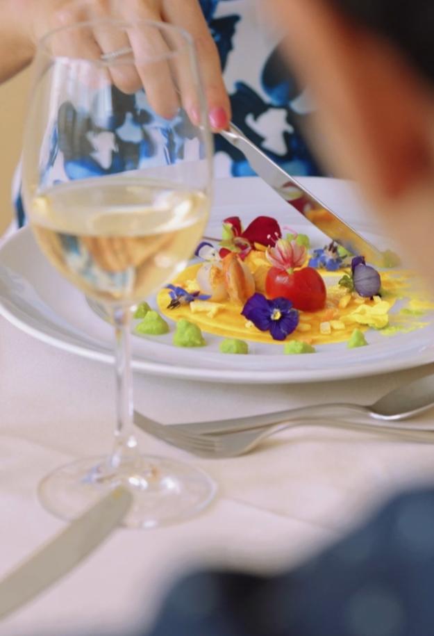 Piatto gourmet con fiori edibili e vino bianco.
