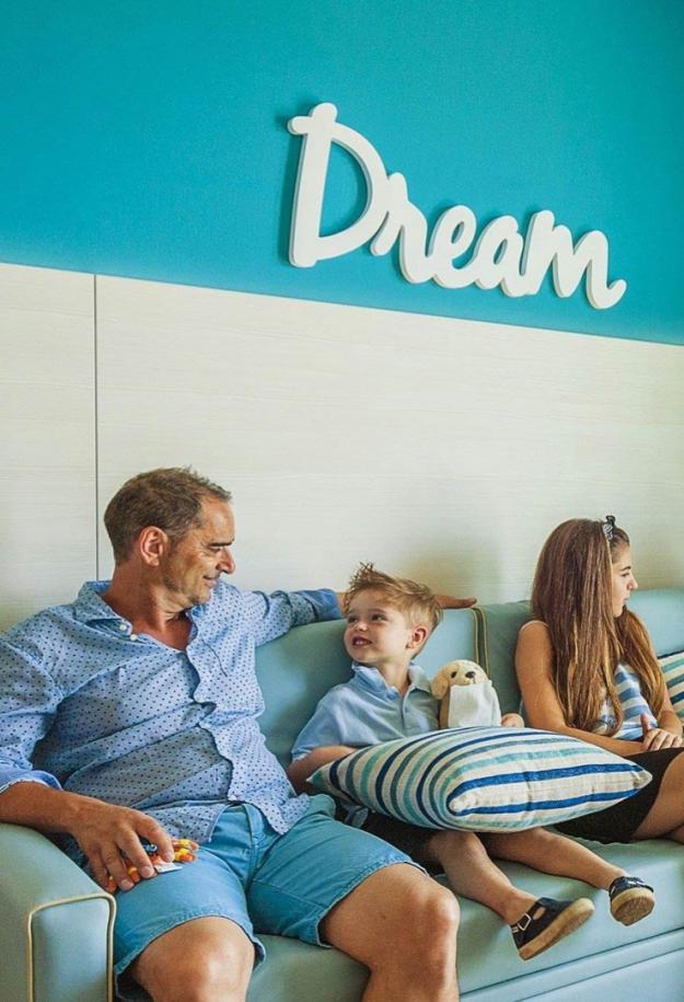 Relaxed family in living room with sea view and 'Dream' sign.