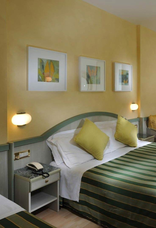 Modern hotel room with double bed and TV.