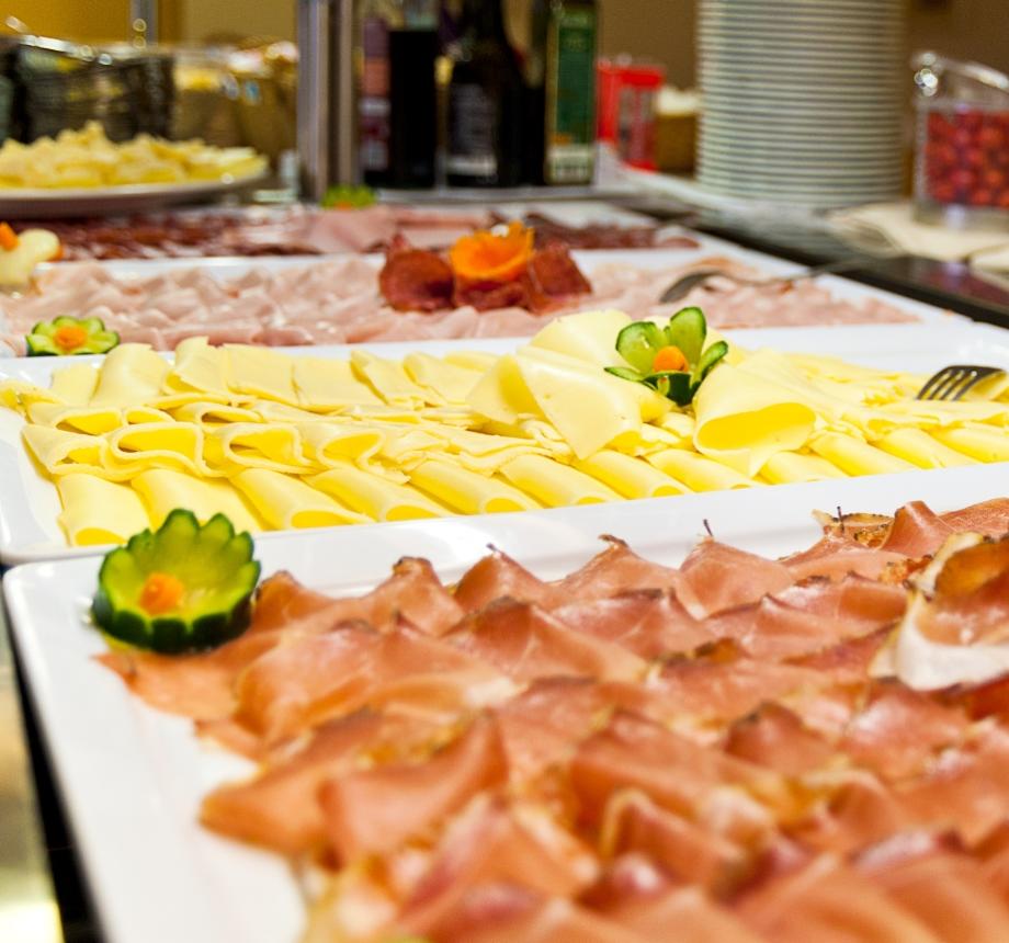 Buffet con affettati e formaggi assortiti su piatti bianchi decorati.