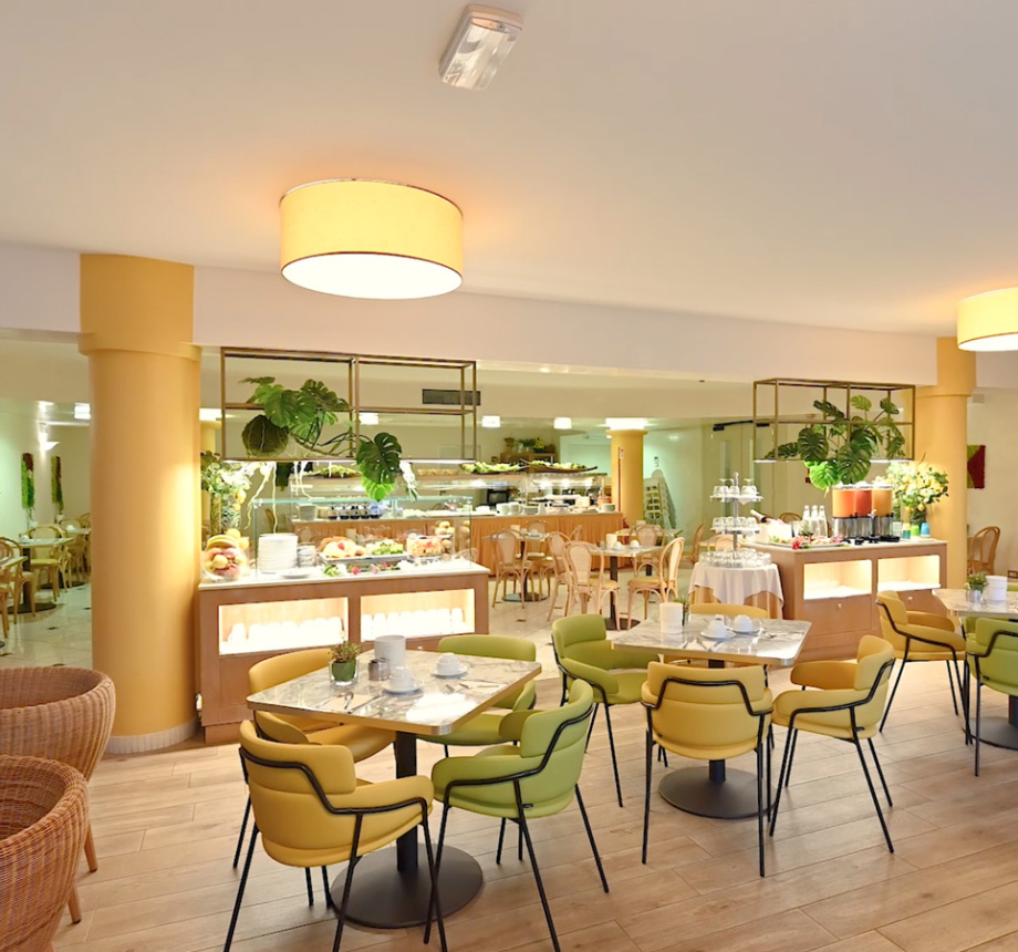 Ristorante moderno con arredamento luminoso e accogliente, piante e buffet.