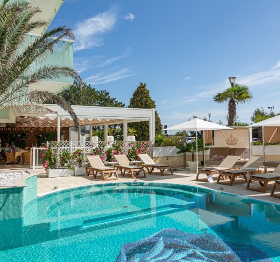 Piscina con lettini e ombrelloni, caffè all'aperto, ambiente rilassante.